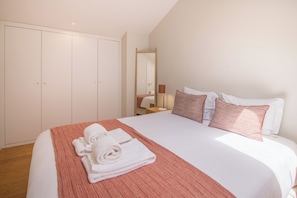 A neatly made bed with white linens and a red striped blanket, a wooden wardrobe, and a mirror on the wall. - ALMADA 151 (Porto)