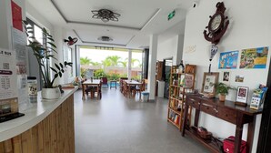 A reception area with a counter, seating area, and a view of the outdoors. - EasyLife Villa Hoi An (Da Nang)