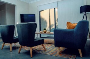 Relax in this stylish living room with a flat-screen TV, comfortable armchairs, and a cozy coffee table.