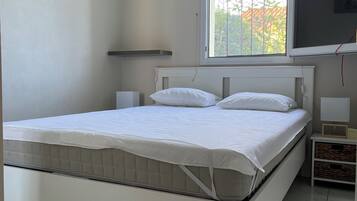 Une chambre à coucher avec un lit, une fenêtre, un tableau et un téléviseur accroché au mur.