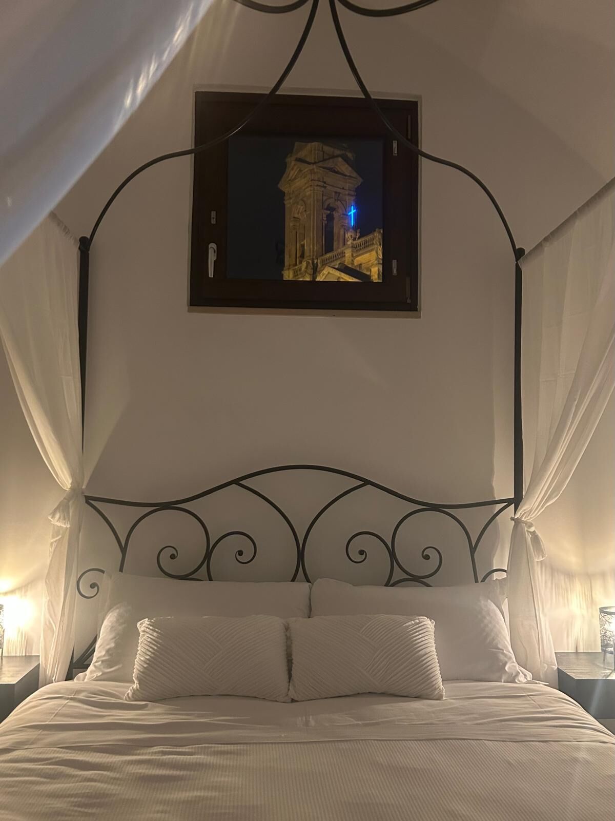 Ein Bett mit Baldachin, ein gerahmtes Bild eines Gebäudes und ein Nachthimmel.
