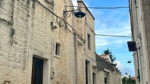 Una calle estrecha con edificios de piedra antiguos, una puerta visible y un cielo despejado.