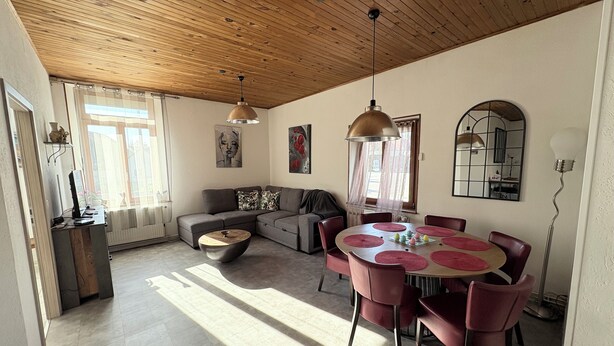 A modern living room with a wooden ceiling, a grey sectional sofa, a round dining table with red placemats, and a large mirror on the wall. - L'escapade du cheval blanc, 3 borders, secure parking  (Kembs)