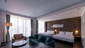 Ein modernes Hotelzimmer mit Bett, Sofa und Schreibtisch.