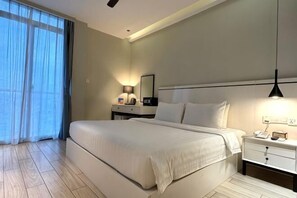 A hotel room with a large bed, bedside tables, a nightstand, a lamp, and a window with curtains.