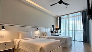 Ein modernes Hotelzimmer mit zwei Betten, einem Deckenventilator und einem großen Fenster mit Vorhängen.