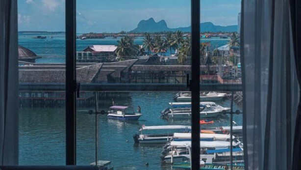 Ein Yachthafen mit vor Anker liegenden Booten, freier Blick auf das Meer und ein entfernter Bergkamm.