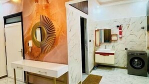Een moderne badkamer met een marmeren vloer, een wastafelmeubel met spiegel, een wastafel en een wasmachine.