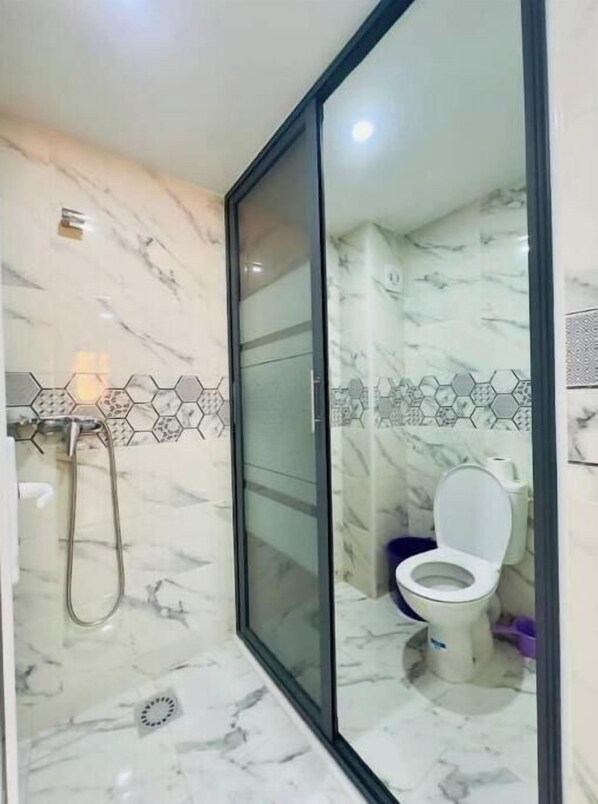 Un baño moderno con ducha de vidrio, inodoro y suelo de mármol.