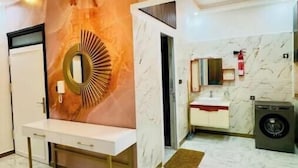 Un baño moderno con suelo de mármol, un lavabo con espejo, un lavamanos y una lavadora.