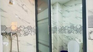 Un baño moderno con ducha de vidrio, inodoro y suelo de mármol.