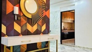 Een modern interieur met een wand met een geometrisch patroon, een ronde spiegel en een witte console tafel met gouden poten.