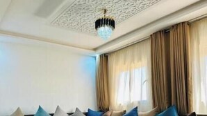 Een moderne woonkamer met een hoekbank, een houten salontafel en een kroonluchter.