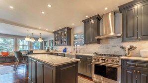 A modern kitchen with dark cabinetry, stainless steel appliances, and a large island.