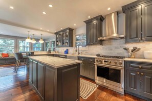 A modern kitchen with dark cabinetry, stainless steel appliances, and a large island.