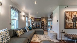 A modern living room with a fireplace, a large sofa, a coffee table, and a painting on the wall.