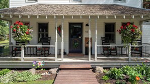 A white house with a porch, a front door, and a number 16 sign.