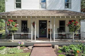 A white house with a porch, a front door, and a number 16 sign.