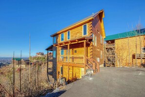 A two-story log cabin with a balcony and a view of the surrounding landscape.