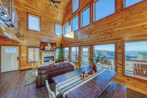 Un intérieur spacieux en bois, avec une cheminée, un canapé en cuir et une table à manger.