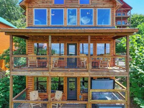 A multi-level wooden cabin with balconies, outdoor seating, and large windows.