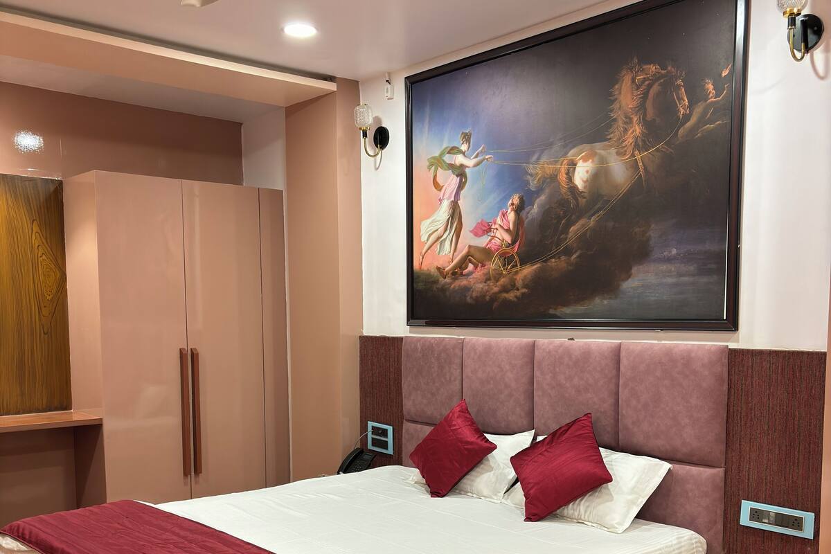 A modern bedroom with a large bed, a ceiling fan, a painting, and a nightstand.