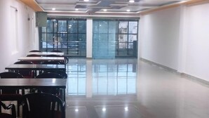 Une pièce spacieuse avec une longue table et des chaises, de grandes fenêtres et un design moderne au niveau du plafond.