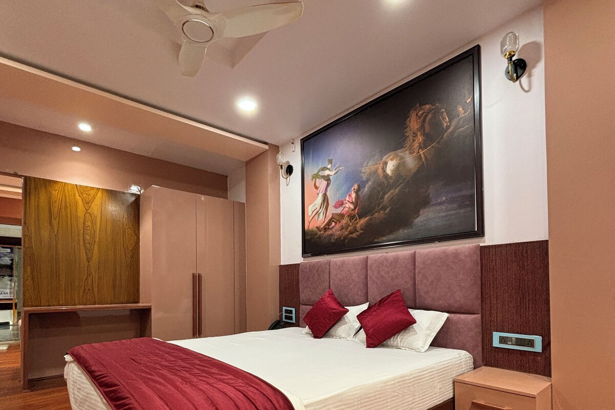 A modern bedroom with a large bed, a ceiling fan, a wall-mounted TV, and a wooden wardrobe.