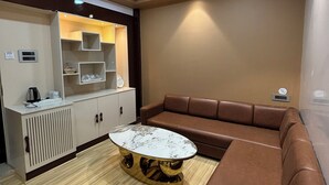 Un salon moderne avec un canapé en cuir marron, une table basse ronde avec un plateau en marbre et un meuble de rangement intégré comprenant des étagères et un téléviseur.