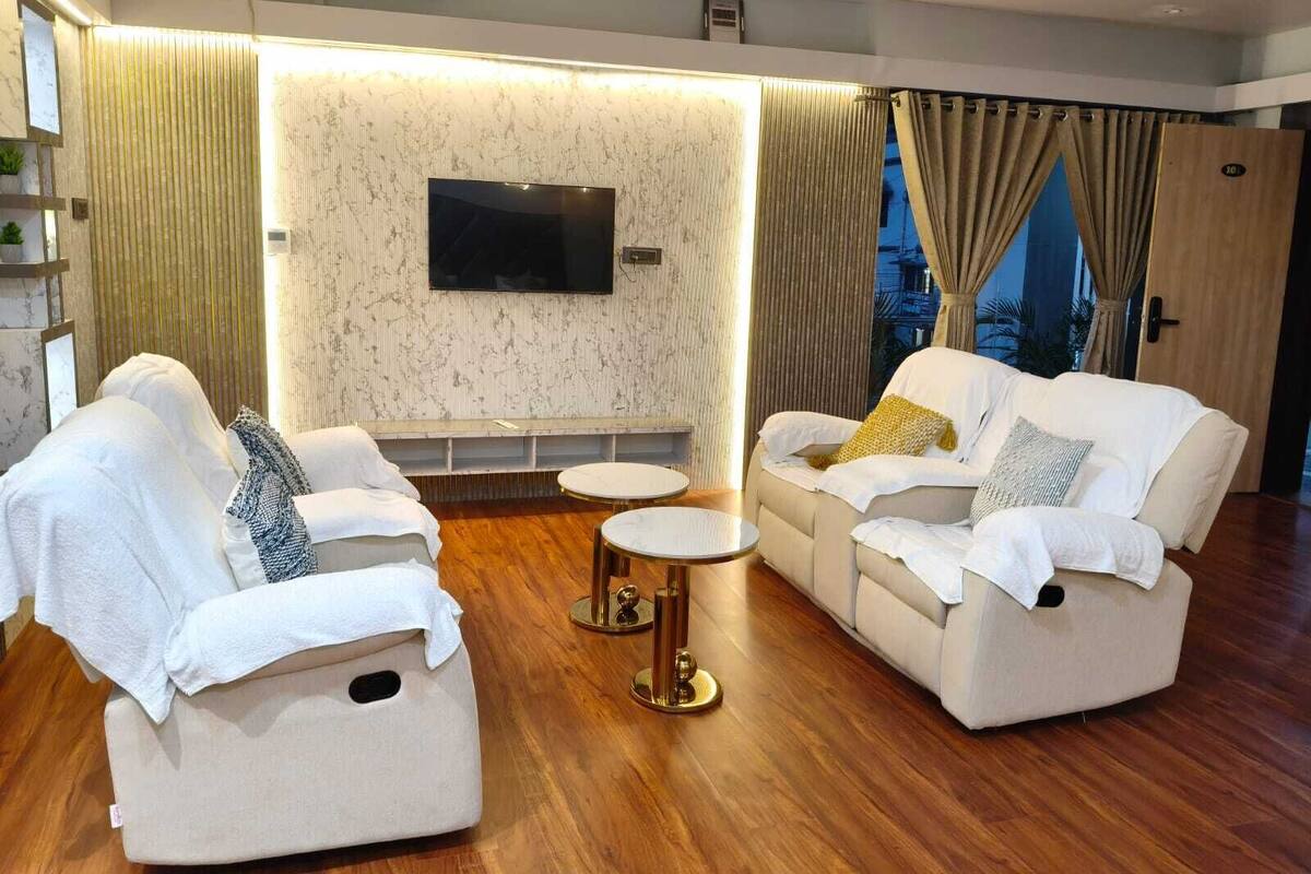 A modern living room with two sofas, a coffee table, and a flat-screen TV mounted on the wall.