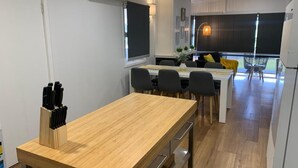 Une cuisine moderne avec une table en bois, des chaises et un bloc à couteaux. On y trouve également un coin repas avec un canapé et une fenêtre.