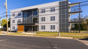 A multi-story residential building with a modern design, featuring balconies, large windows, and a well-maintained lawn.