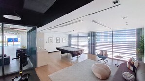 A modern living room with a pool table, a sofa, and a massage chair. - Belgravia Heights 1 - Tranquil One Bedroom in JVC (Jumeirah Village Circle)