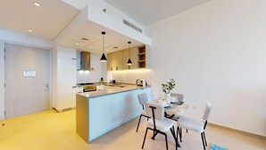 A modern kitchen with a central island, pendant lighting, and a dining area with a table and chairs. - Belgravia Heights 1 - Tranquil One Bedroom in JVC (Jumeirah Village Circle)