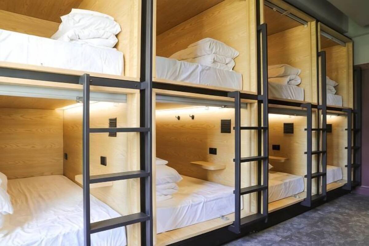 Bunk beds with wooden frames and white bedding, arranged in a row.