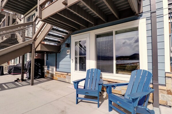 A building with a covered outdoor area, a staircase, and two blue Adirondack chairs.