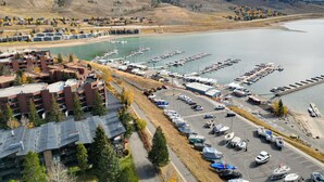 A marina with boats docked, a parking lot, and buildings with a modern architectural style.