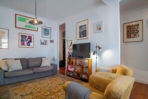 Relax in this stylish living room with a large flat-screen TV, comfortable sofa, and armchair.