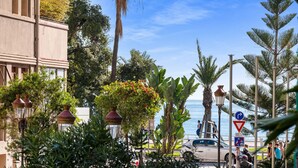 Une rue côtière bordée de palmiers, illuminée par des lampadaires et offrant une vue sur la mer.