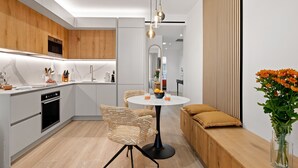 Une cuisine moderne dotée d’un îlot central, d’un coin repas avec une table ronde et d’un espace détente avec un canapé et des coussins.