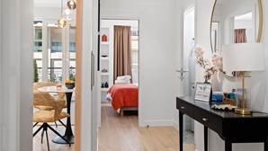 Une chambre d’hôtel avec un lit, un bureau doté d’une lampe, un miroir et une vue sur le balcon extérieur.