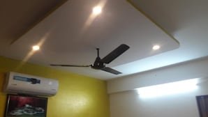A room with a ceiling fan, an air conditioning unit, and a light fixture. - Maruthi Residency (Bengaluru)