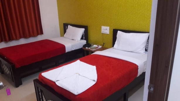 A hotel room with two beds, each with a red bedspread and white pillows. - Maruthi Residency (Bengaluru)