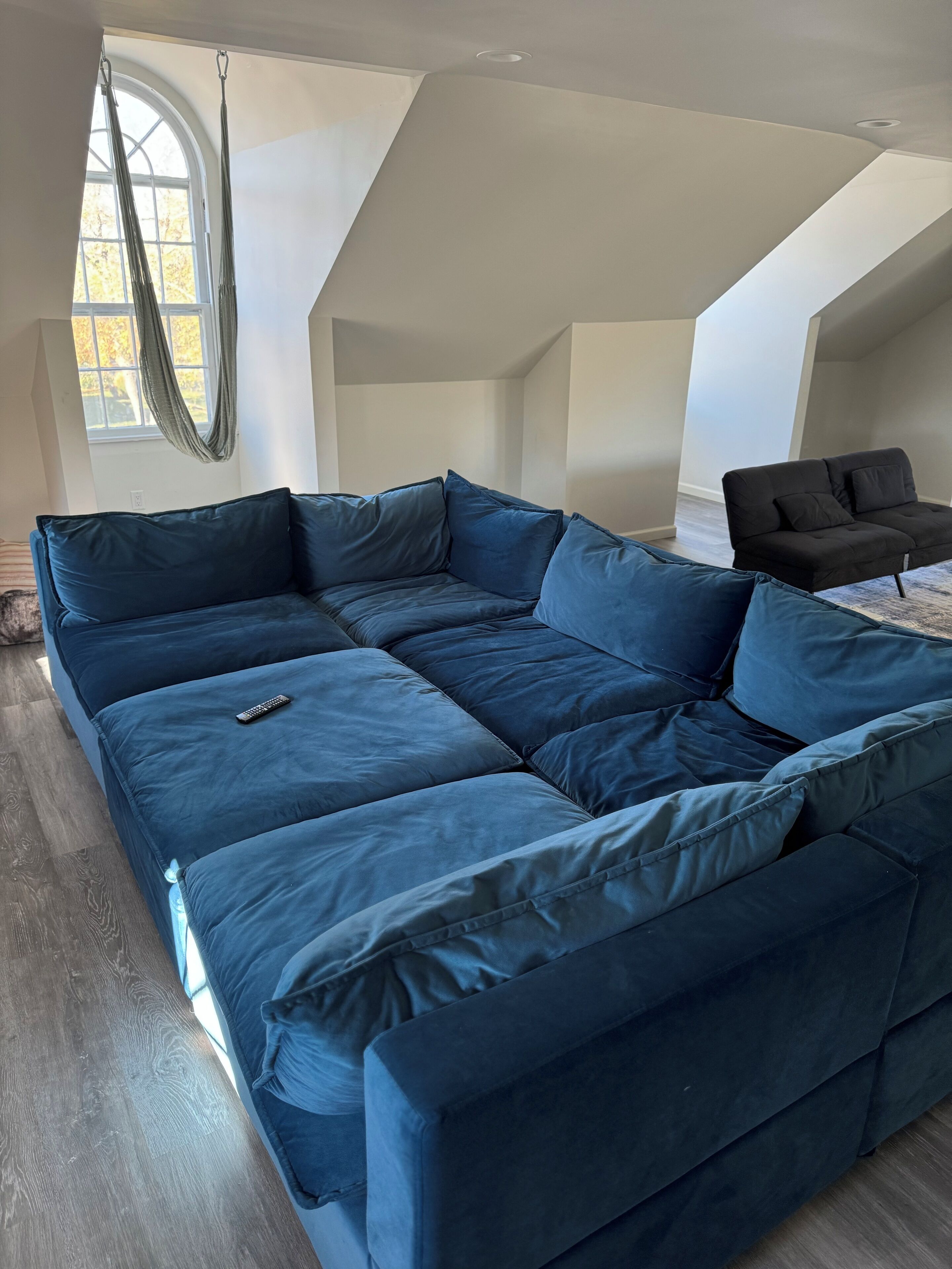 Un sofá modular grande en una habitación con techo alto y ventana amplia.