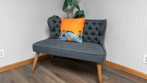 A grey upholstered bench with wooden legs, a zebra-patterned cushion, and a large green plant. - Sleeps 12 , Safe area , Close to top attractions (St. Louis)