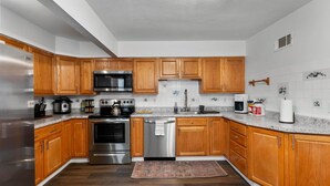 A kitchen with wooden cabinets, stainless steel appliances, a microwave, a stove, and a dishwasher. - Sleeps 12 , Safe area , Close to top attractions (St. Louis)