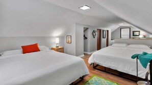 A hotel room with two beds, a nightstand with a lamp, a small table with a vase, and a framed picture on the wall. - Sleeps 12 , Safe area , Close to top attractions (St. Louis)