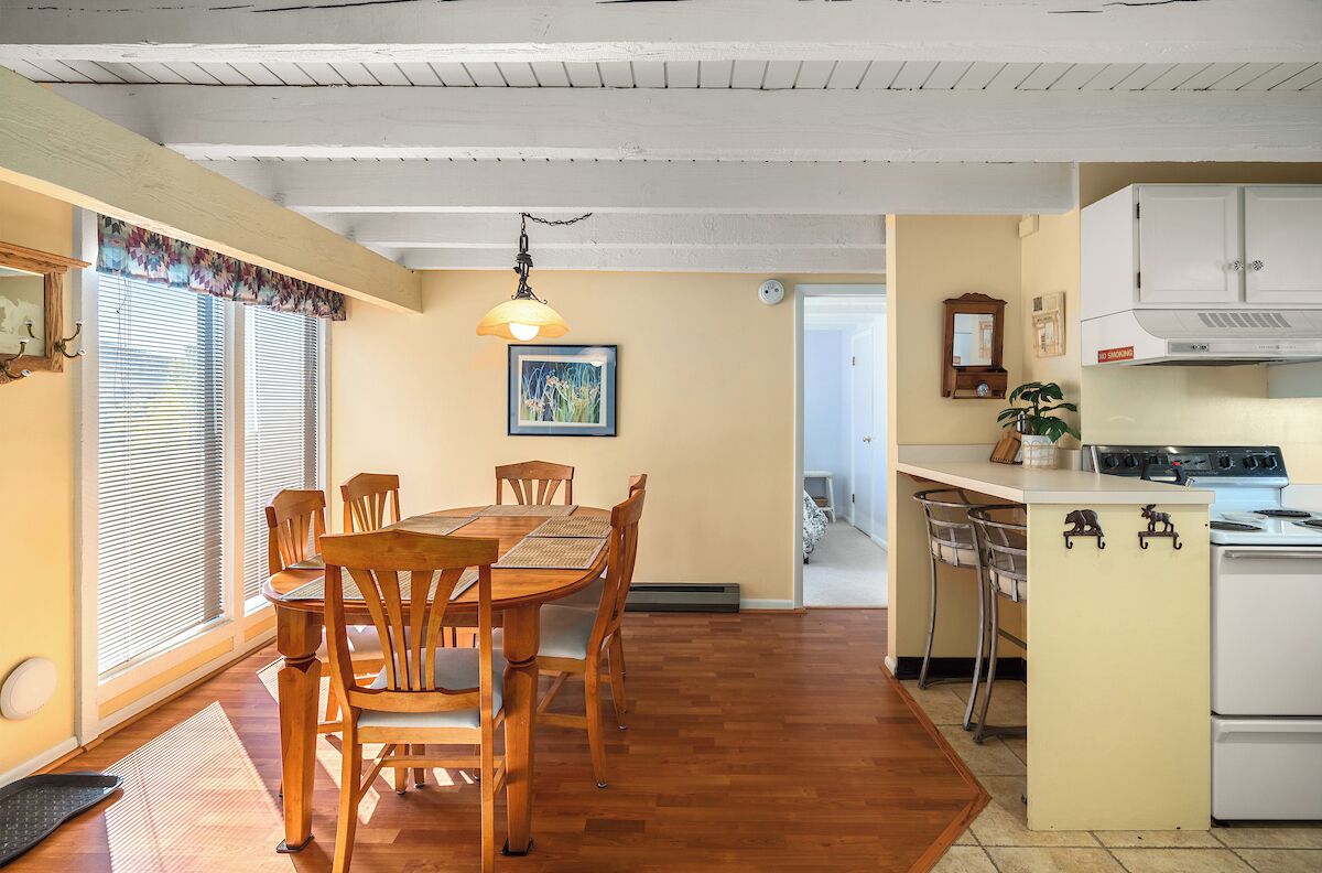 Ett kök med träskåp, en spis och en matplats med ett bord och stolar.