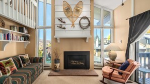 A cozy living room with a fireplace, a rocking chair, a sofa, and a bookshelf. - Bright, Spacious Ski Condo Close to the Resort! (Steamboat Springs)