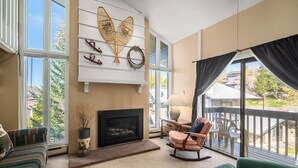 A living room with a fireplace, a rocking chair, and a sofa. - Bright, Spacious Ski Condo Close to the Resort! (Steamboat Springs)